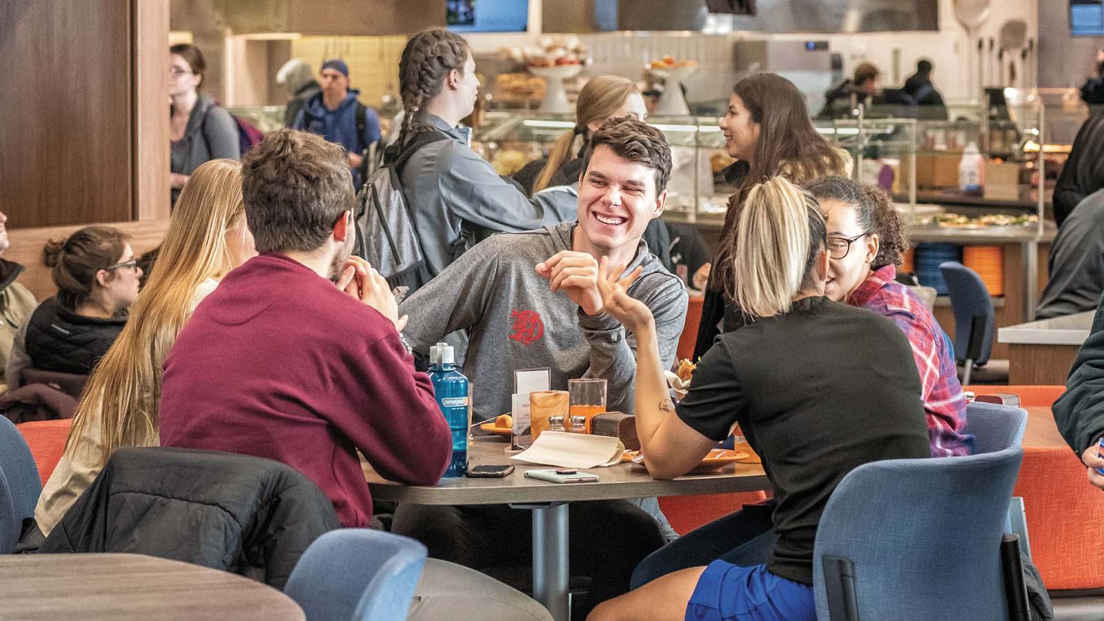 一群学生在鸟巢校园餐厅一起吃饭，谈笑风生